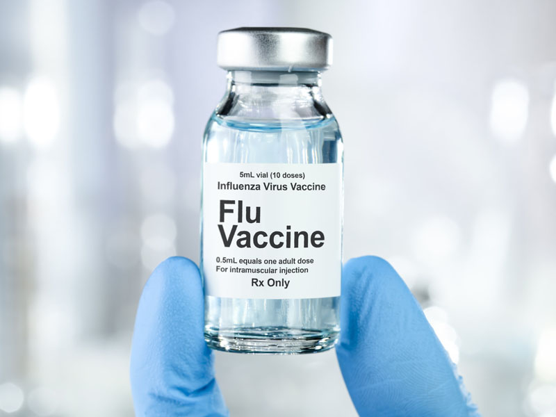 Flu vaccine vial held in a gloved hand